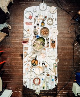 Esstisch nach einem gemeinsamen Dinner mit Geschirr, Gläsern und Essensresten – Vogelperspektive auf festliche Tafelszene. Frederick Vidal – visual research